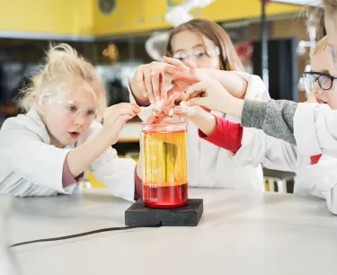 Flera barn experimenterar inne i Universeums kemilabb iklädda rockar och skyddsglasögon.