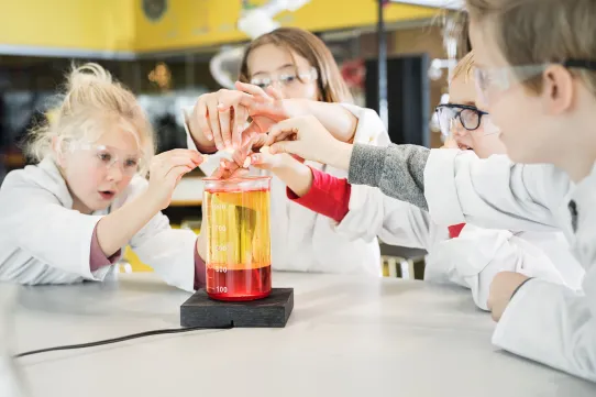 Flera barn experimenterar inne i Universeums kemilabb iklädda rockar och skyddsglasögon.